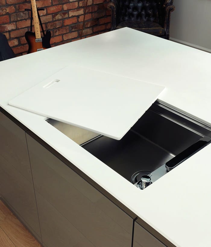 Sliding a cover manually over the kitchen sink to make it invisible.