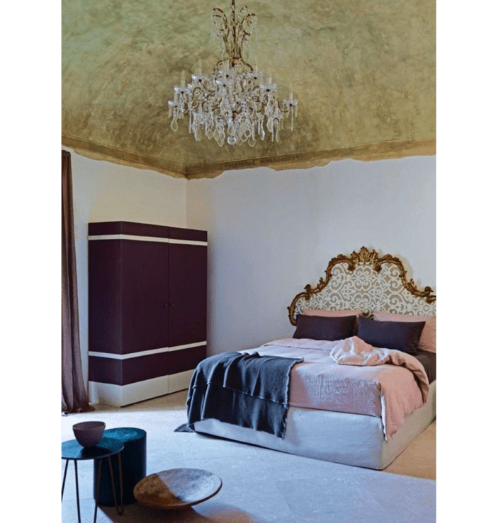 Bedroom with vaulted ceiling painted in gold. The glass chandelier draws the attention up even more.