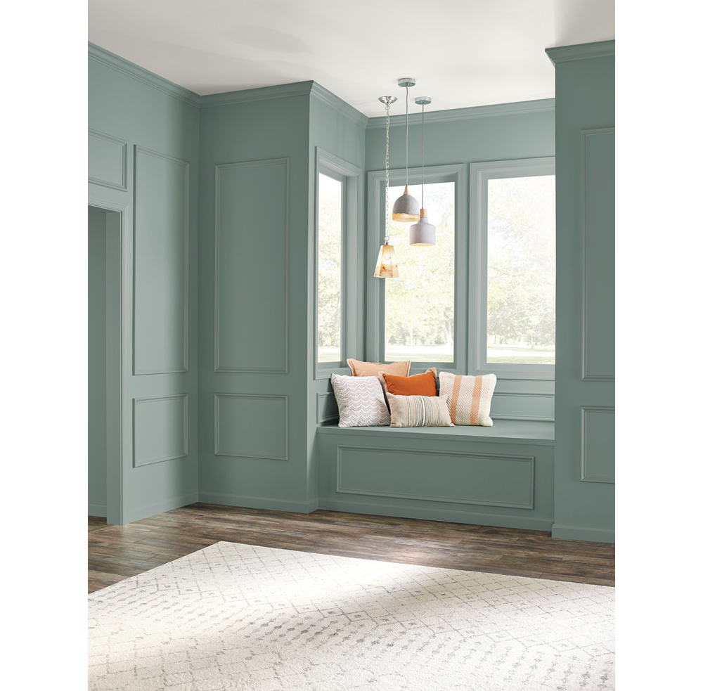 Window seat in a classic home. The walls are painted with In the Moment (2018 colour of the year by Behr). To complete the seating area, white suspension lights and cushions in the tones of white and orange.