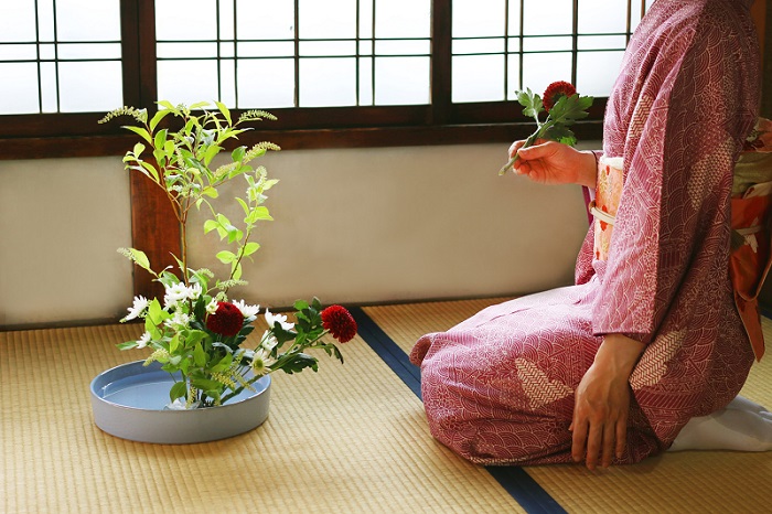 Woman arranging flowers in an Ikebana composition.