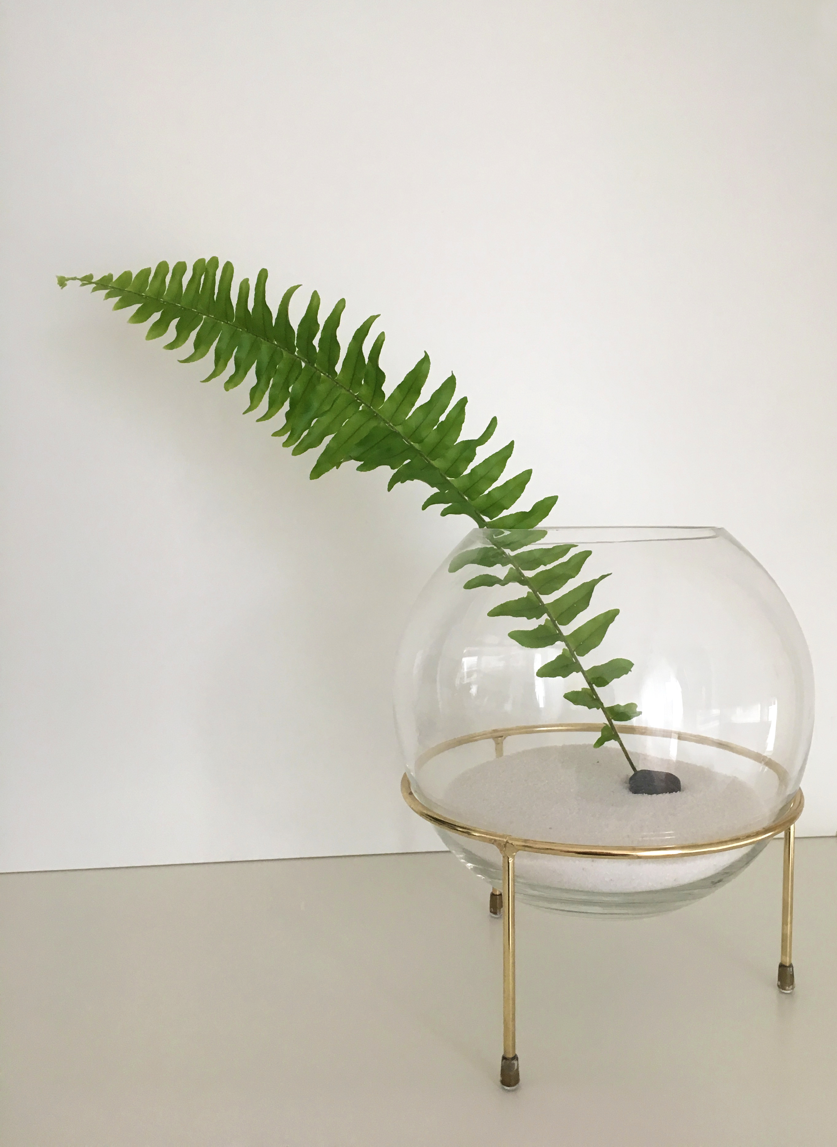 Minimal sculptural vase with a single-leaf arrangement.