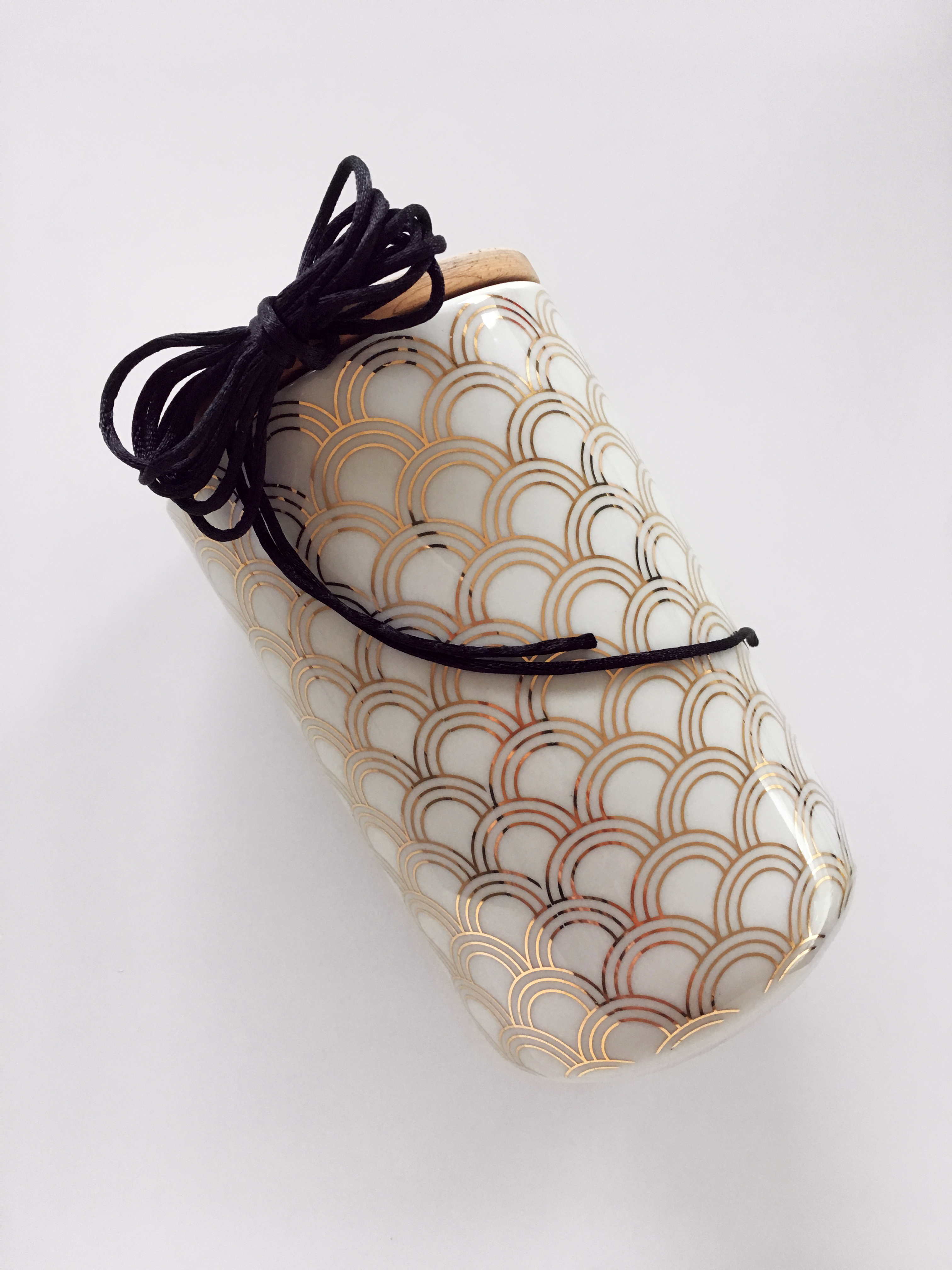 Gift contained into a white and gold patterned jar as an example of sustainable gift wrapping.