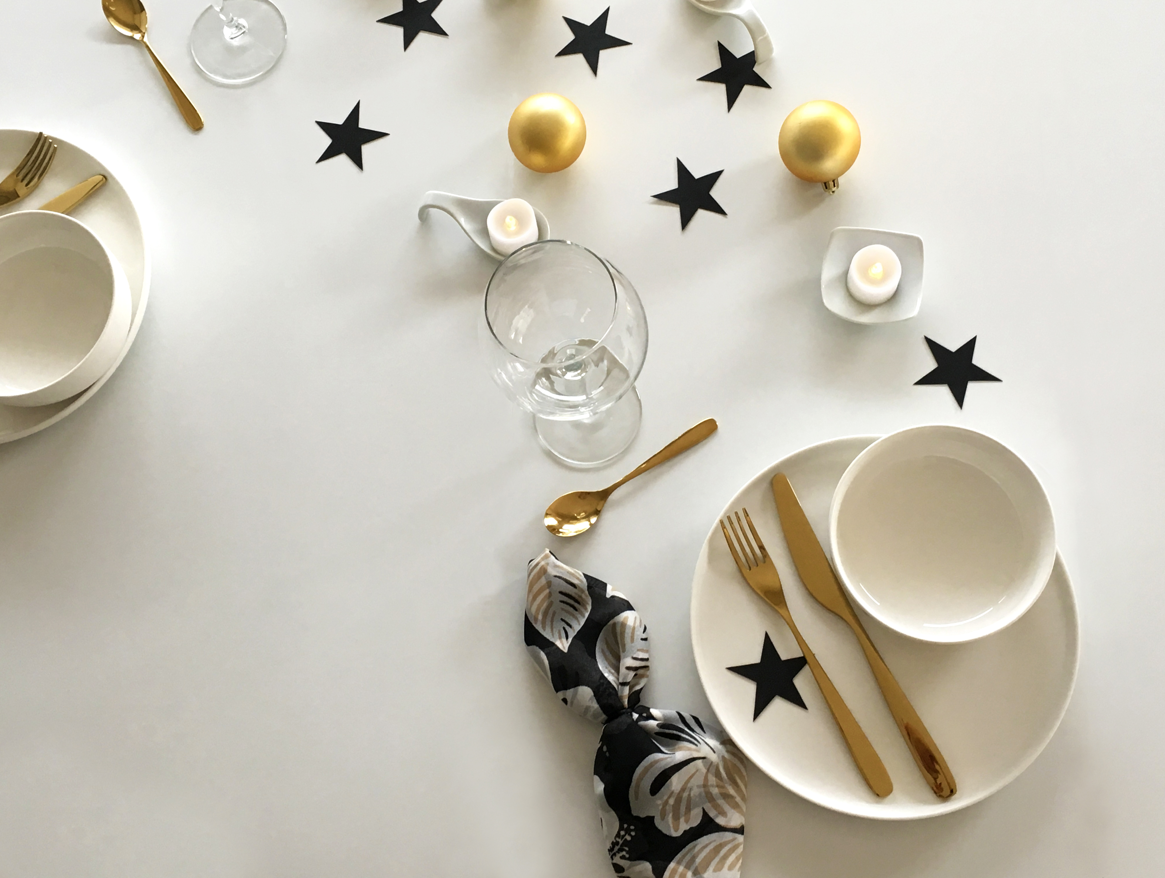 View of the same minimal modern Christmas table setting with two places arranged on consecutive sides of the table.