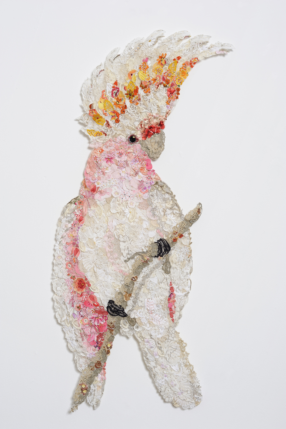 Textile art parrot made up of reused pieces of needlework, pins and tulle.