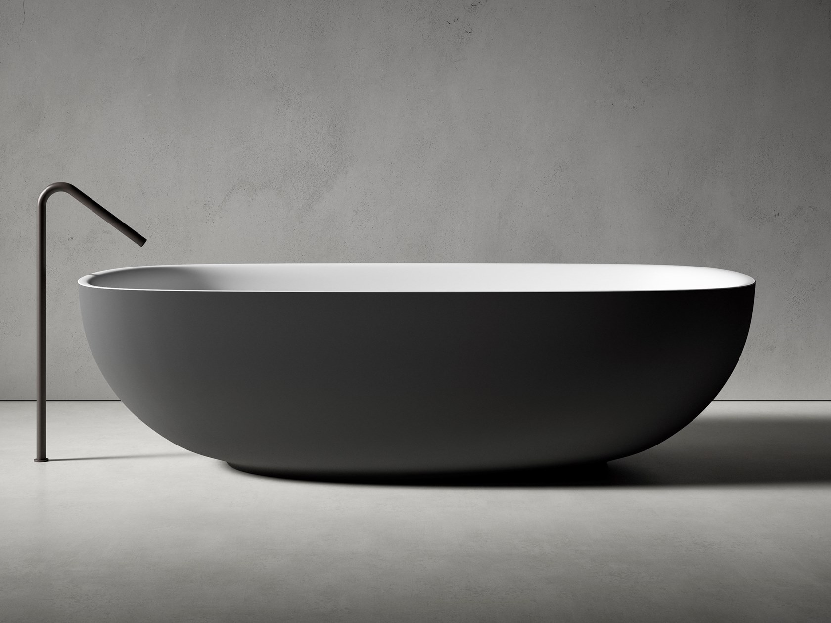 Bathtub with an oval shape and rounded floor-mounted faucet.