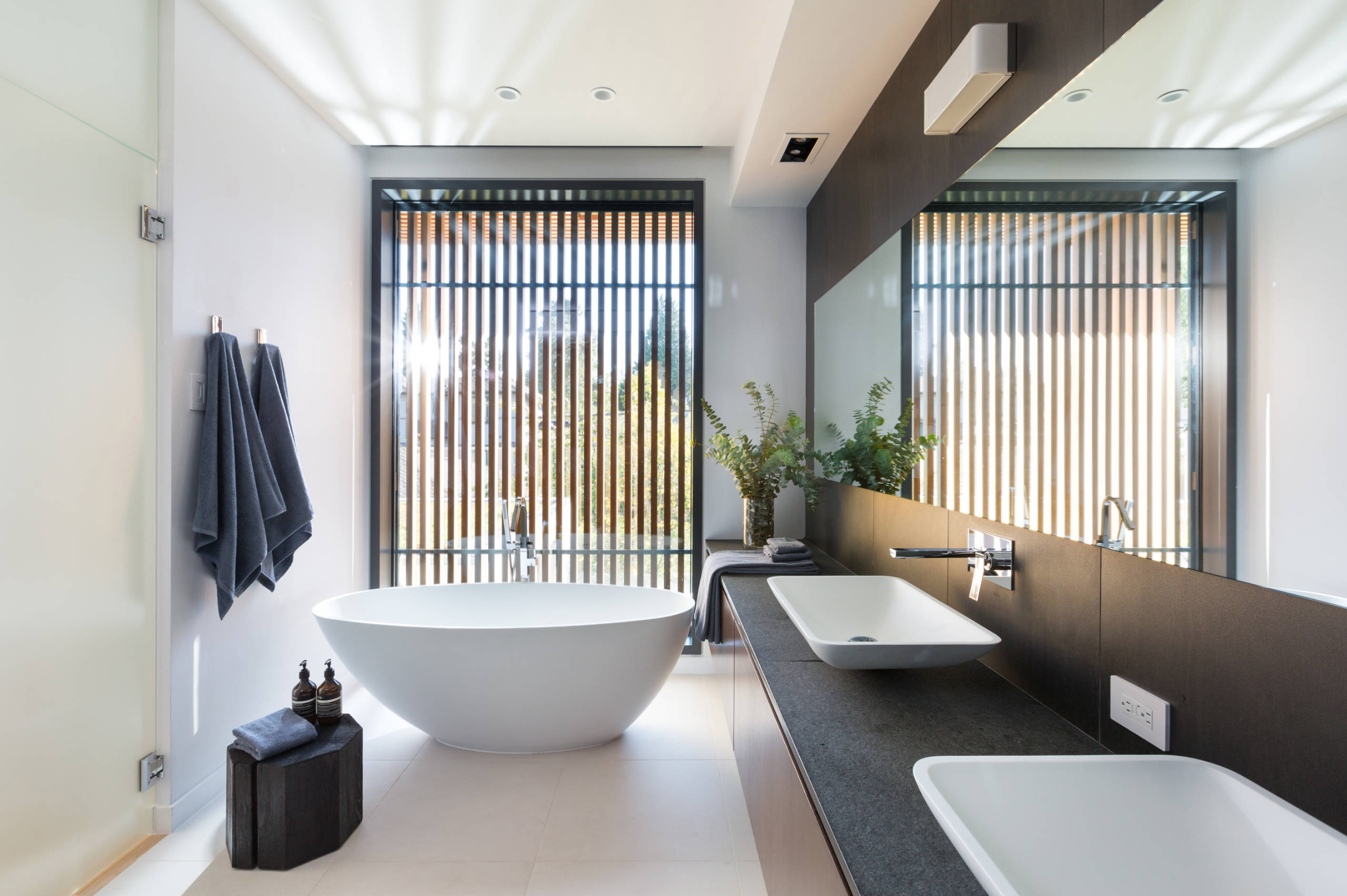 Natural bathroom design filled with natural light. A vertical wall panelling adds privacy