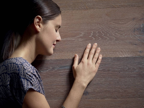 A woman touching a wooden surface.