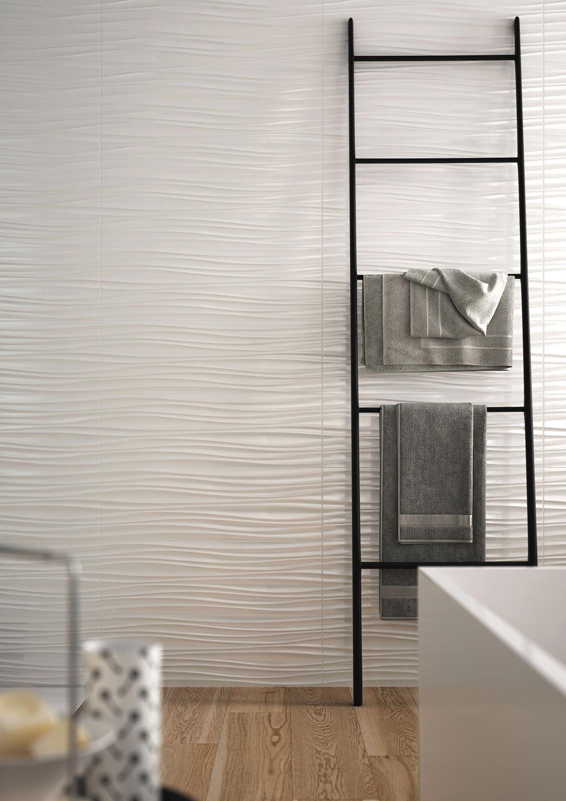 Bathroom wall with textured tiles recalling the wavy shape of sand moved by the wind.
