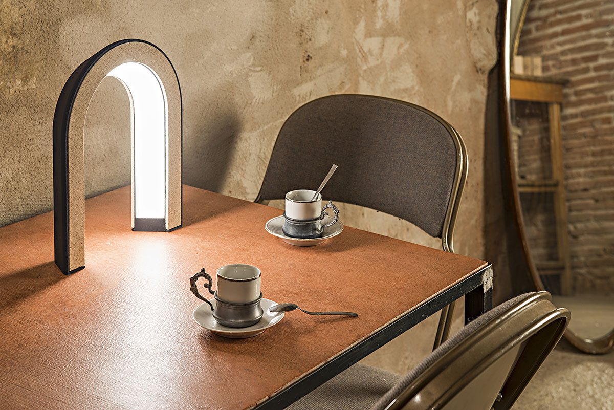 Arc-shaped lamp made with coffee grounds, sitting on a table.