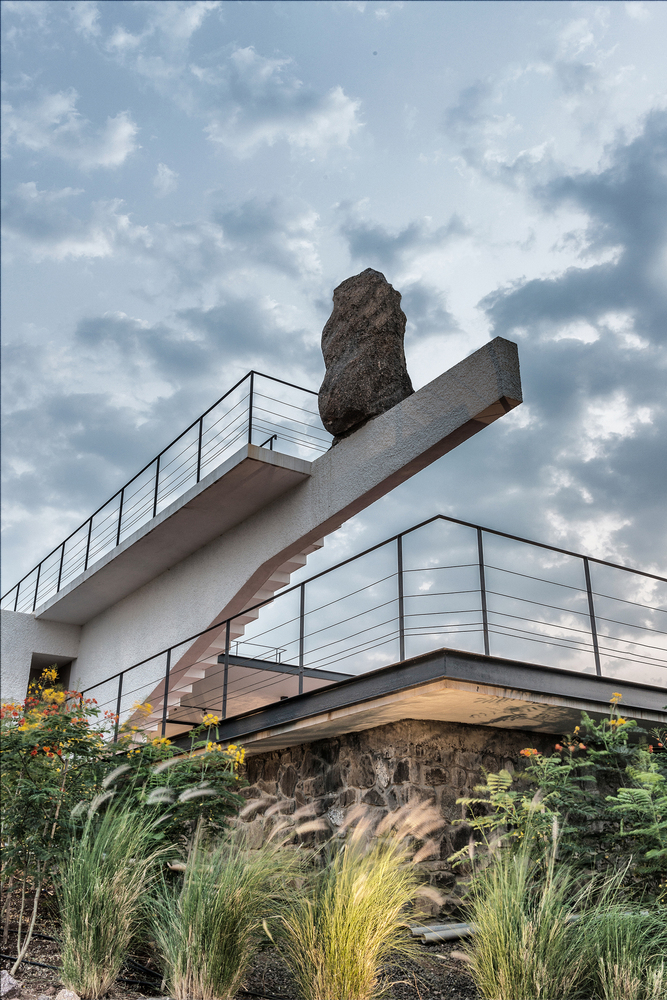 Exterior cantilever pillar feature supporting a huge rock that seems teetering.