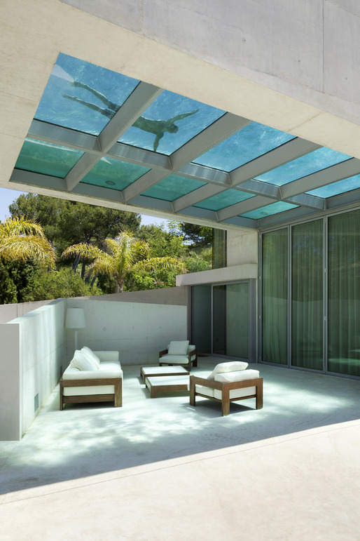 Pool with a glass bottom located over a seating area.