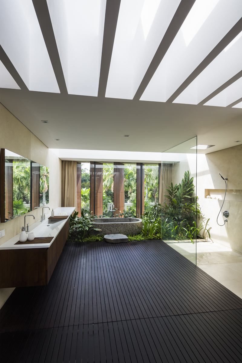 Bathroom facing a huge window with plenty of plants down the bathtub.
