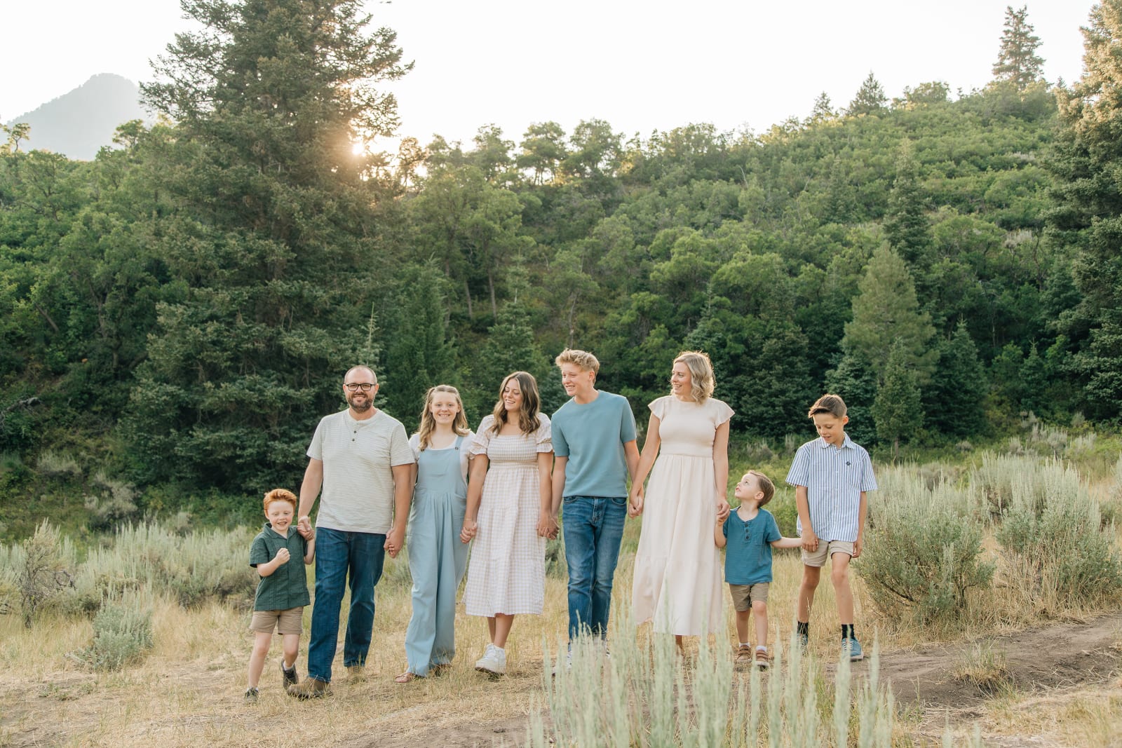 Amy O'Neal with her husband and their six kids, walking hand in hand through a mountain meadow at sunset in Utah
