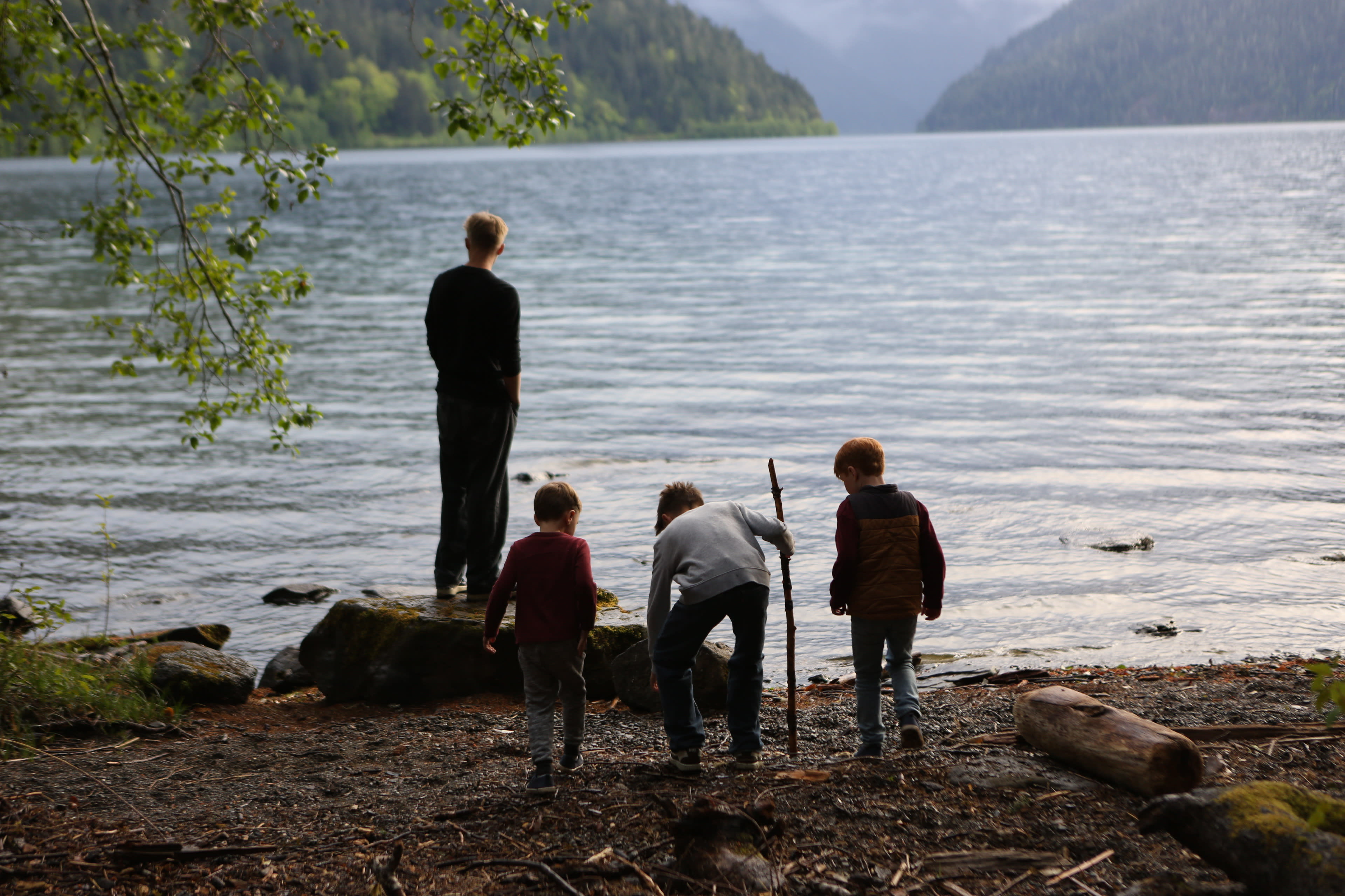 Family at the edge of Lake Crescent looking out over the clear blue water, Olympic National Park, Washington