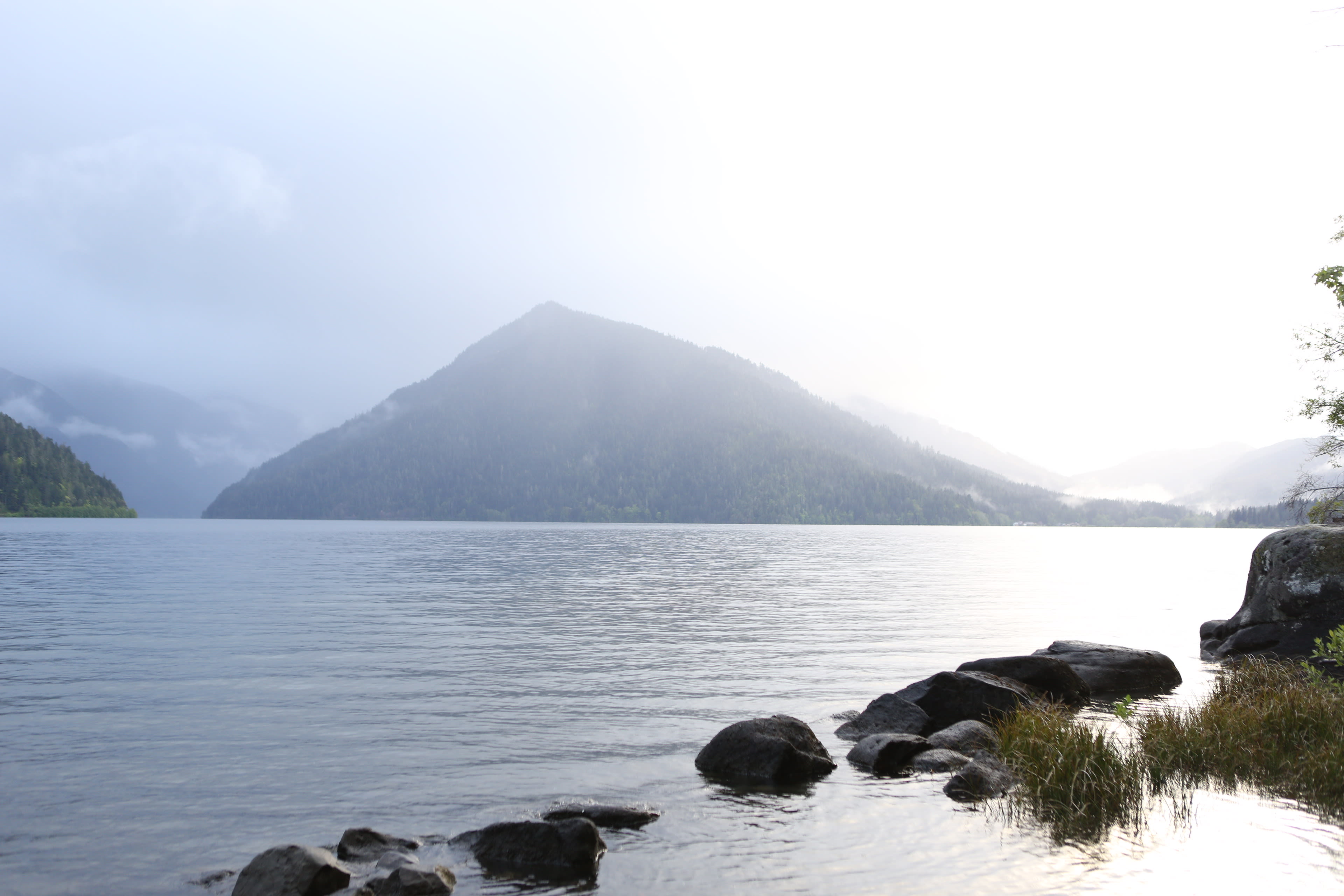 Forested mountain with clouds rolling off the summit above the still water of Lake Crescent, Olympic National Park, Washington