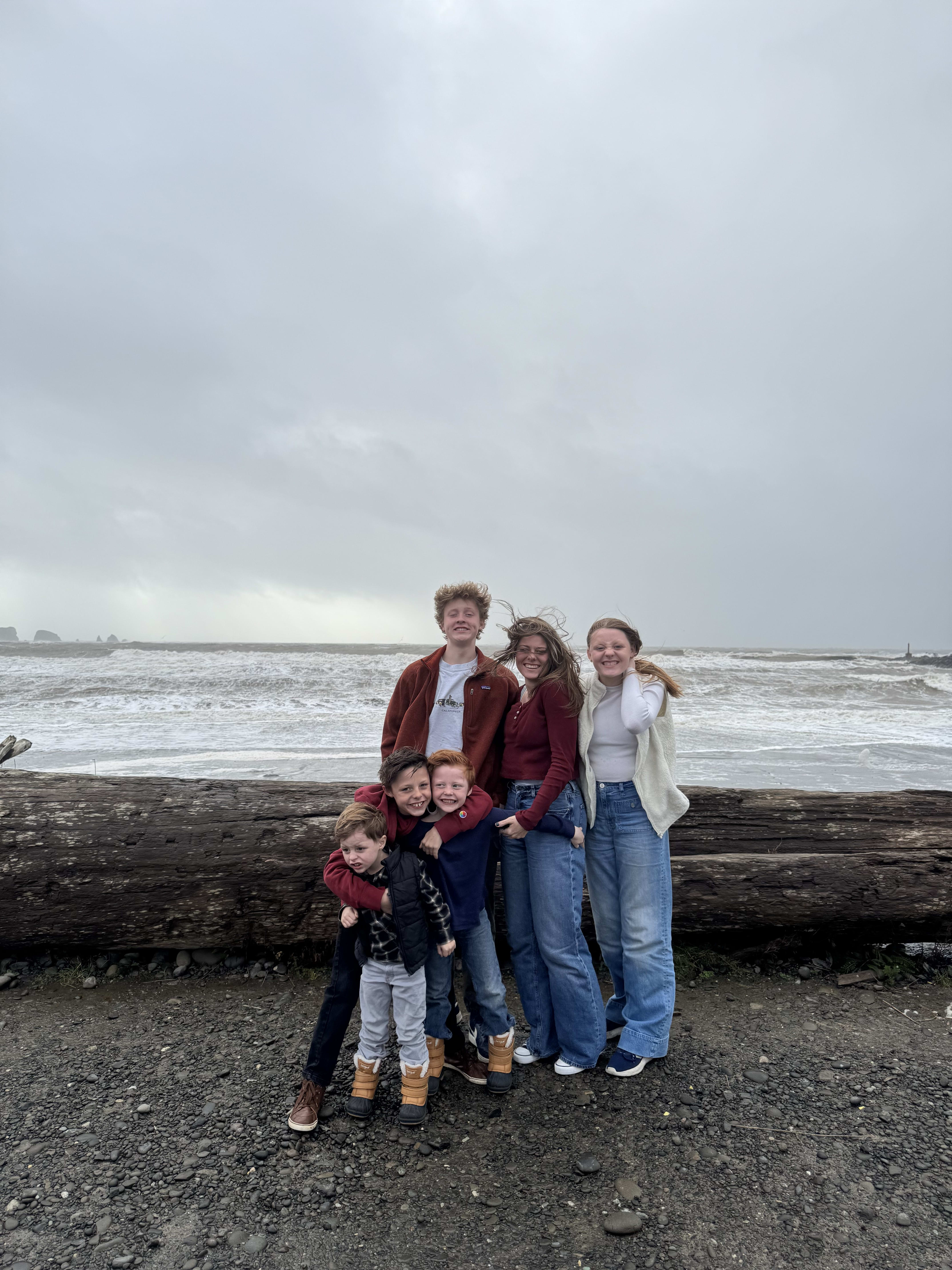 Family on the beach with driftwood and sea stacks at La Push, Washington