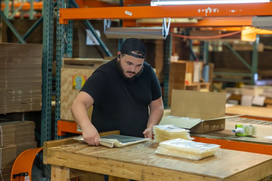 A Simple Distribution team member packing product by hand at a workbench
