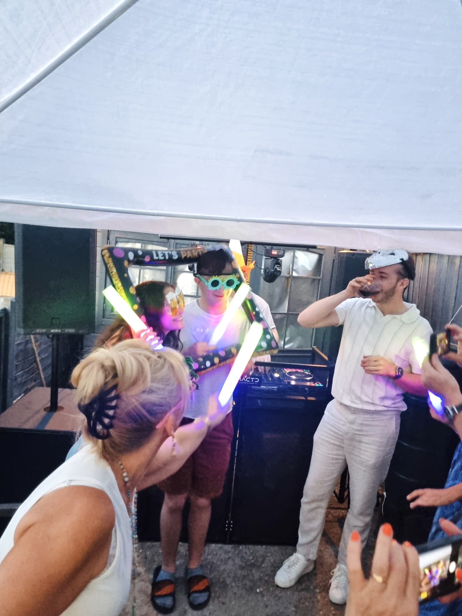 Guests dancing with glow sticks at a DFRACTD garden marquee party