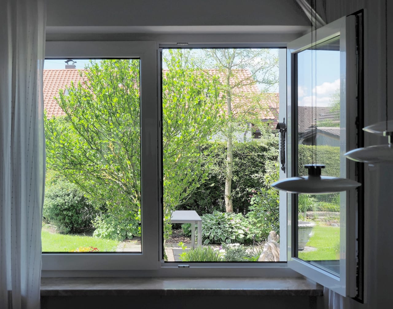 Janela térrea aberta com vista para jardim, representando ventilação natural automatizada