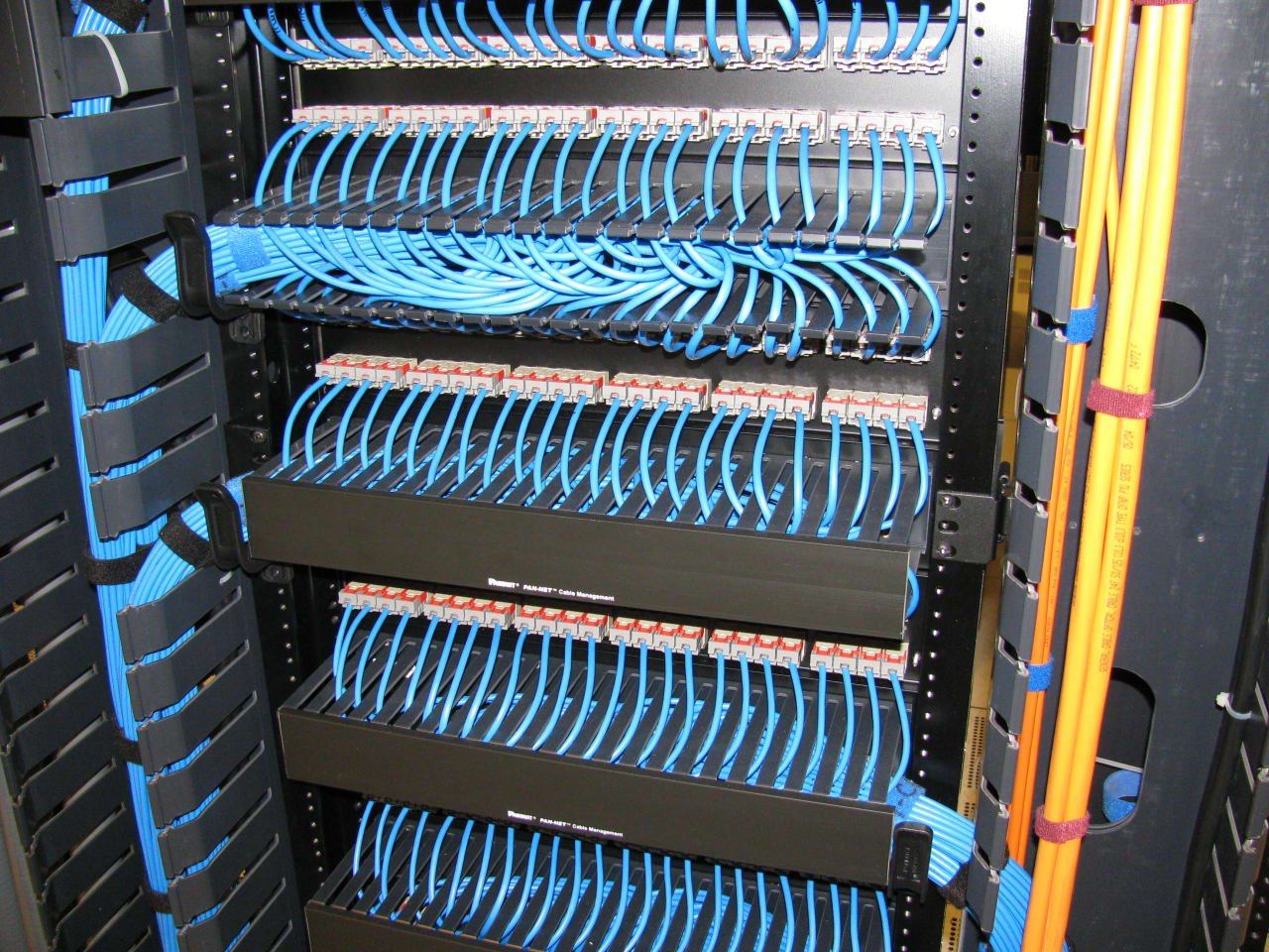 Parte traseira de patch panel Cat6 com vários cabos de rede conectados e organizados