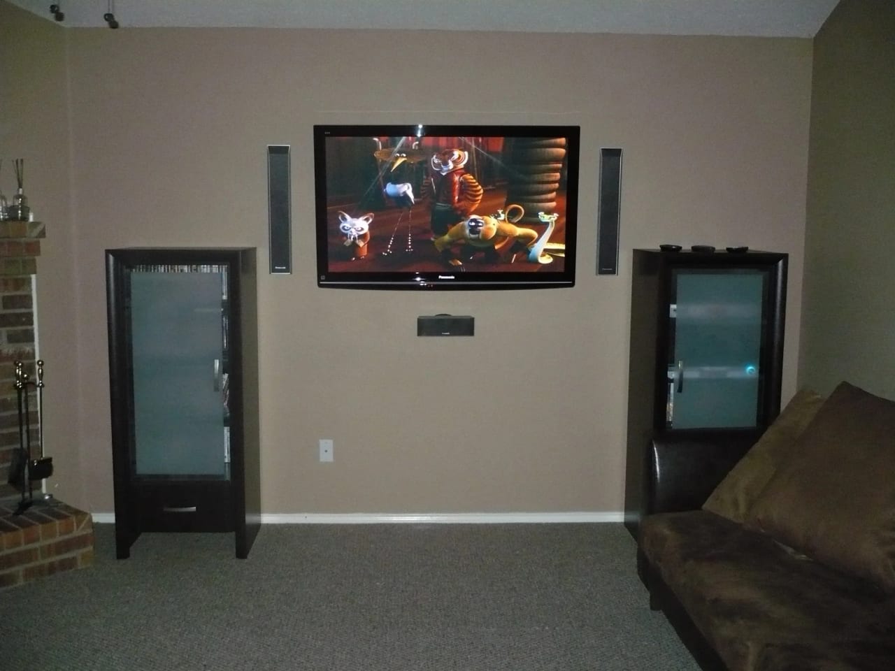 TV instalada na parede de uma sala com caixas de som embutidas no teto ao redor do ambiente