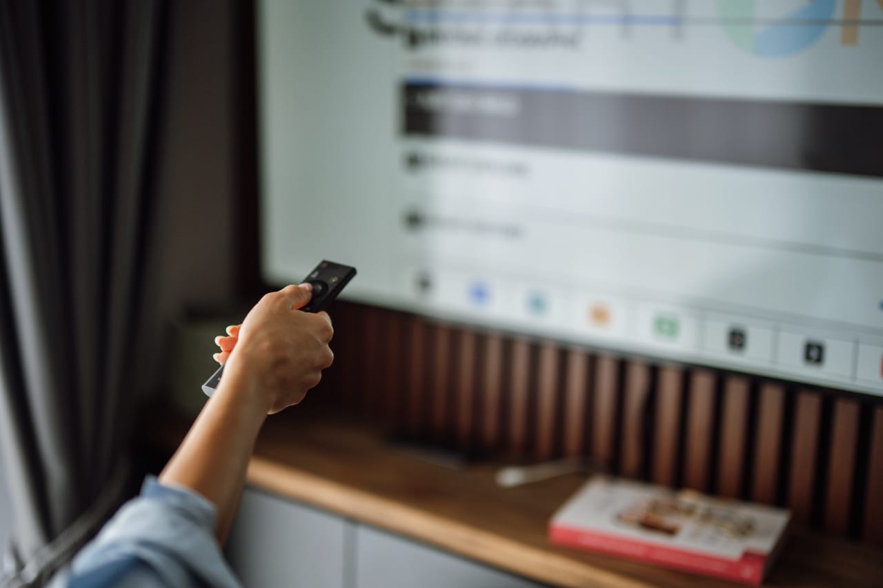 Pessoa usando controle remoto para navegar em menu de TV em uma sala residencial