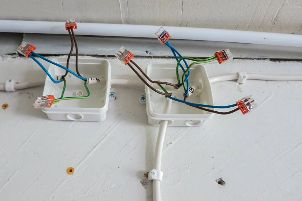 Caixa de passagem aberta com fios elétricos e conectores, representando instalação de módulos relé mini