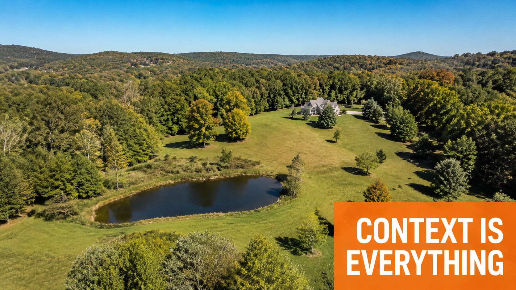 An aerial view of a large house situated on five acres of green land with a small pond.