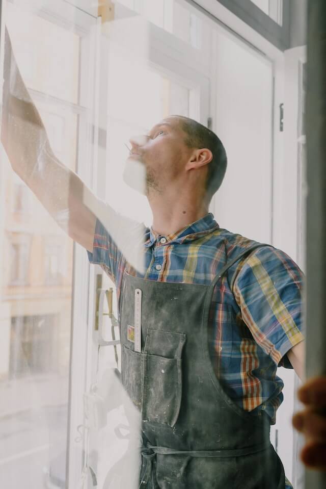 man sealing and installing window in room