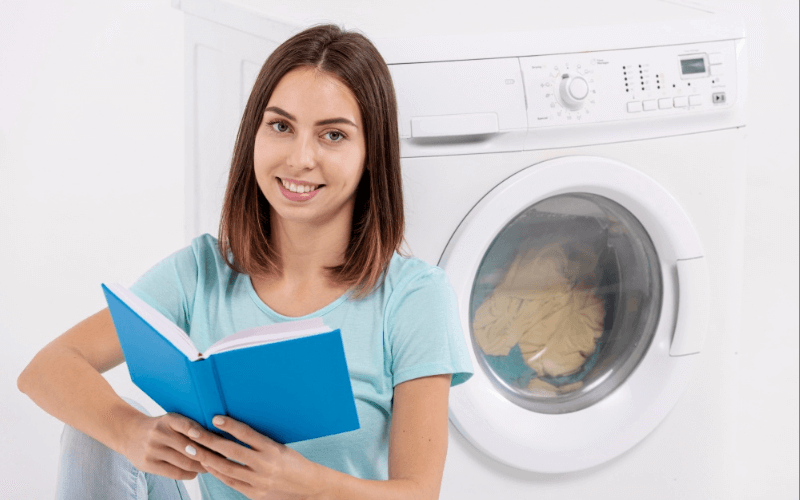 a young women is reading a guide for cleaning a dryer