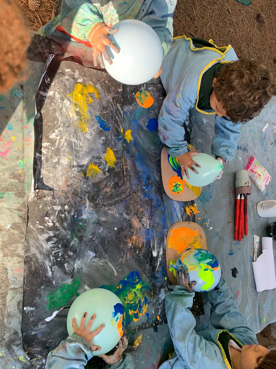 Niños y niñas pintando planetas con globos y pintura de colores