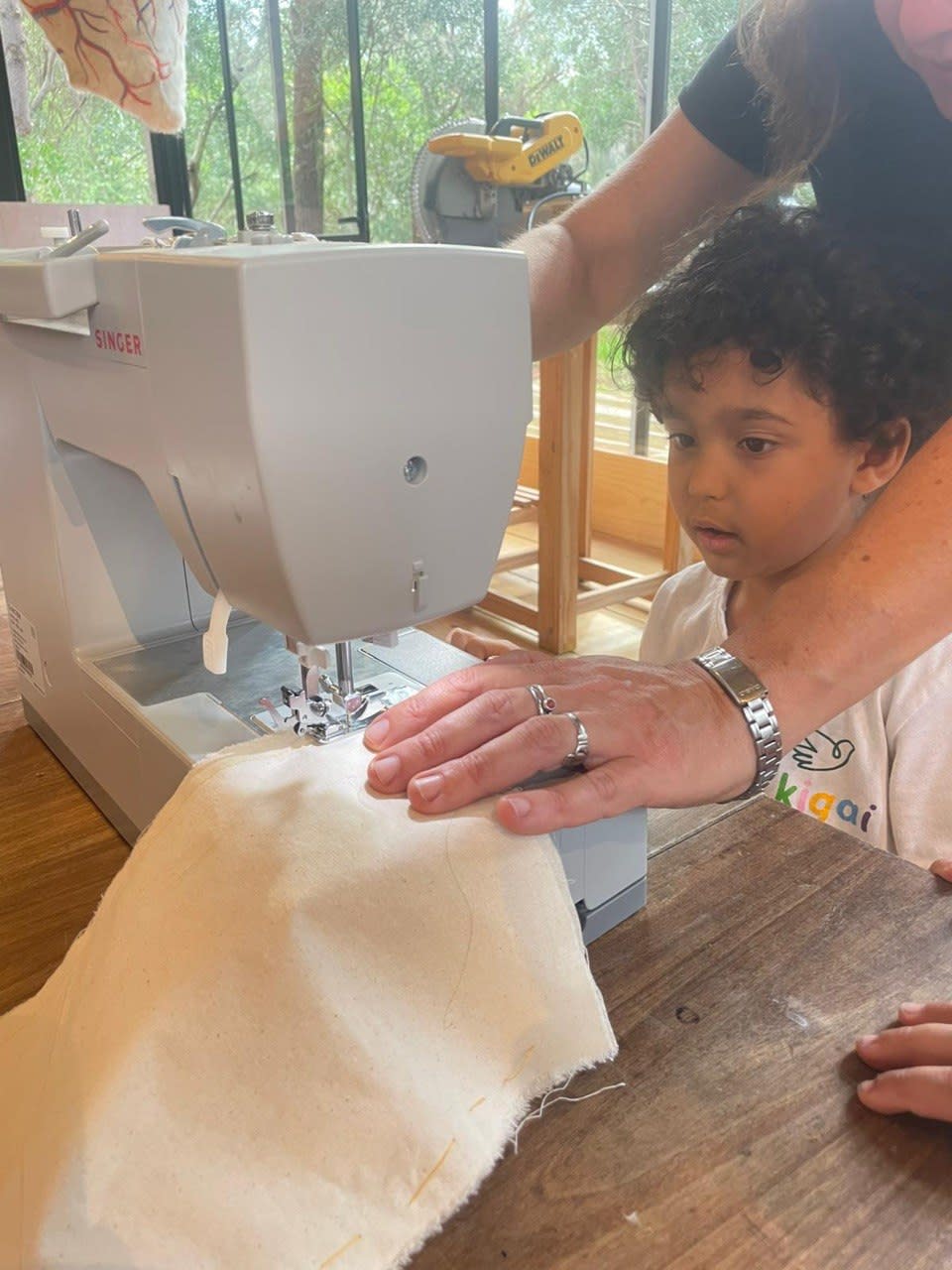 Niño usando la máquina de coser con acompañamiento adulto