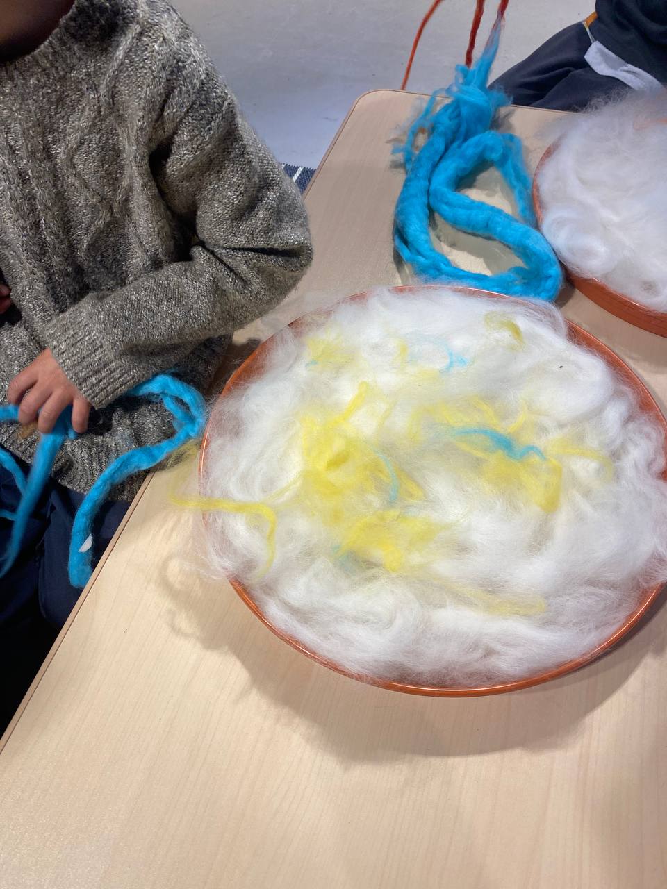 Niños trabajando con lana y vellón blanco y de colores