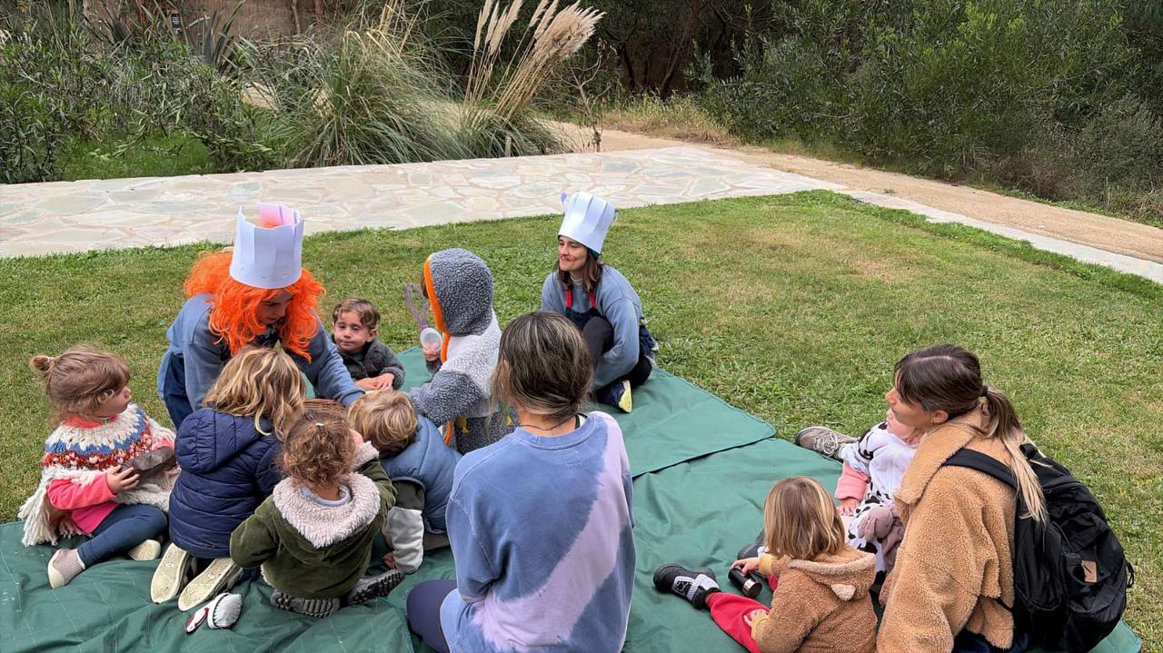 Niños y niñas reunidos en ronda al aire libre durante el juego de cocina