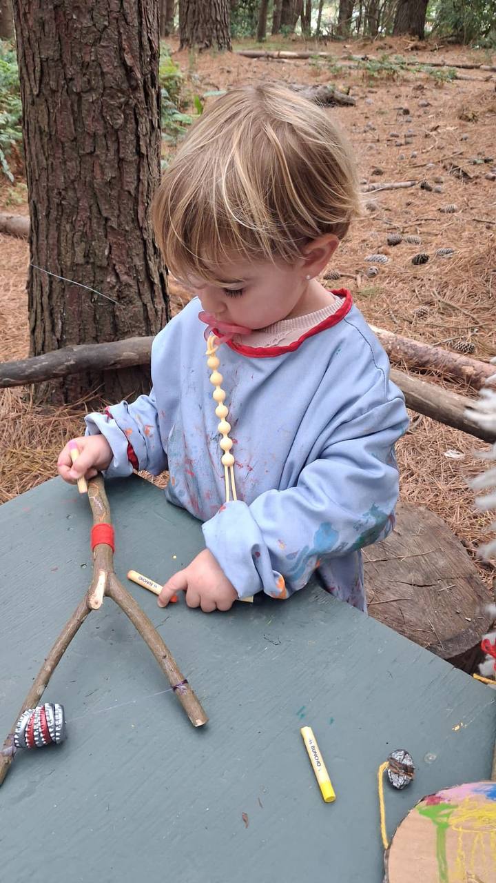 Niña trabajando con ramas y materiales sonoros sobre la mesa