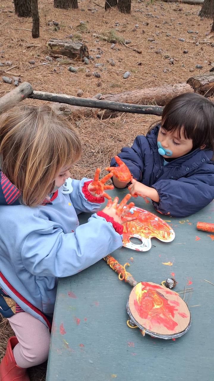 Niños explorando pintura y materiales para sus instrumentos