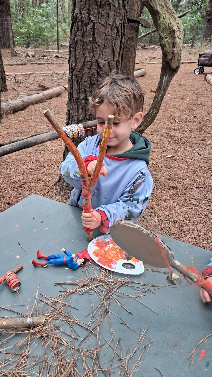 Niño explorando un instrumento construido con ramas y elementos naturales