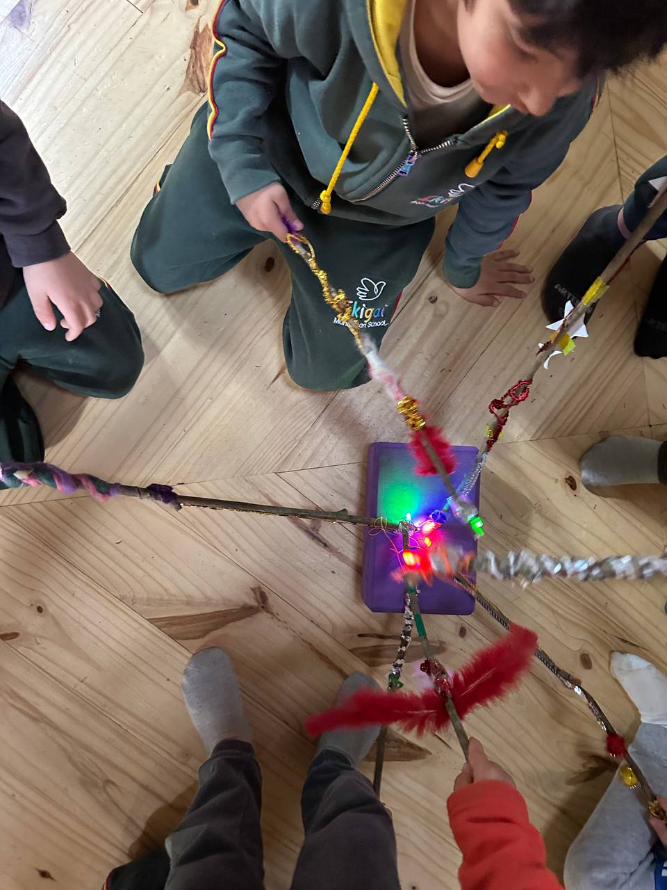 Niños explorando movimientos con varitas luminosas y registrando trazos de luz mediante fotografías de larga exposición.