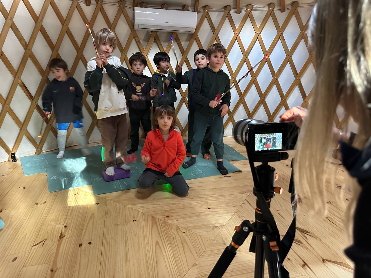 Niños explorando movimientos con varitas luminosas y registrando trazos de luz mediante fotografías de larga exposición.