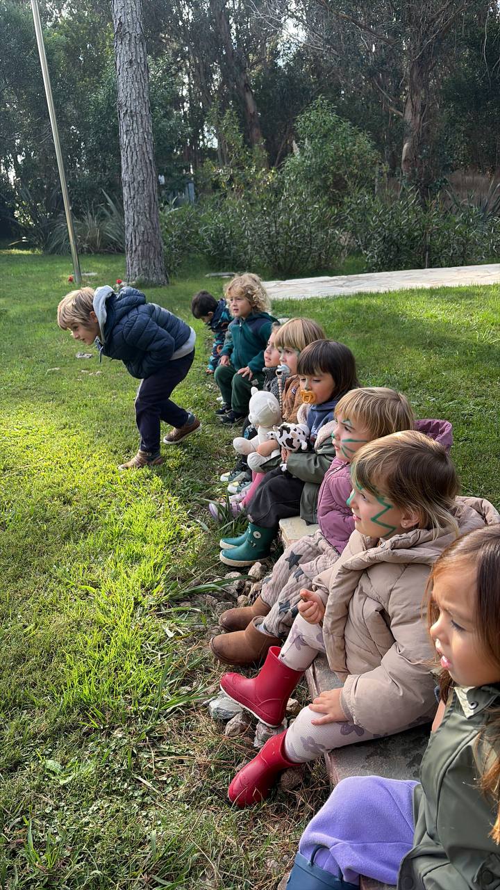 Ninos sentados al borde del bosque observando una consigna grupal