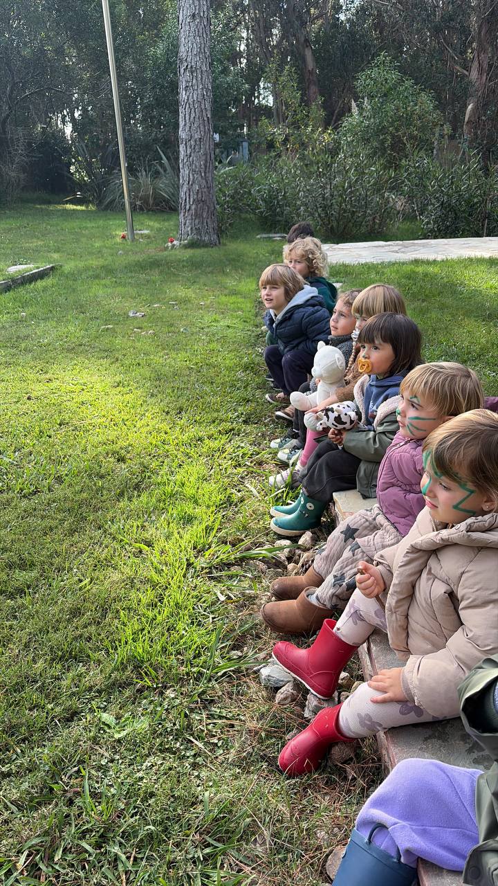 Grupo de ninos esperando atentos sentados junto al pasto