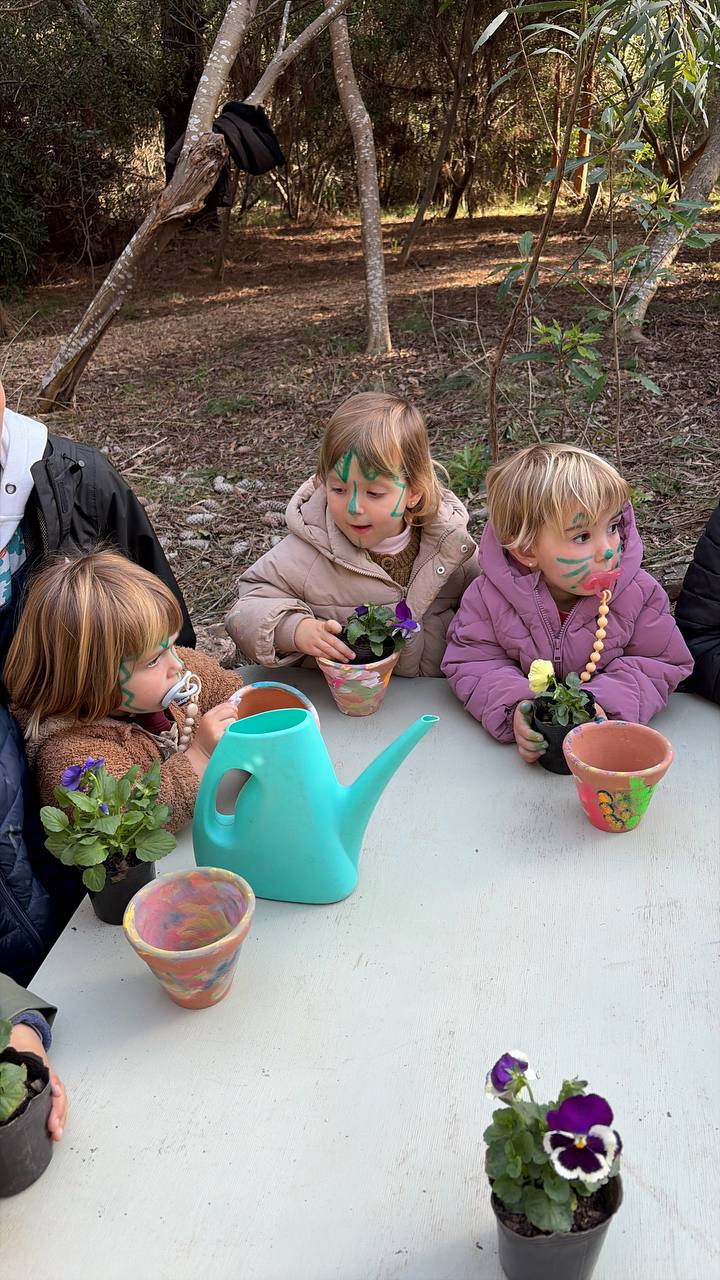 Ninos con plantas, macetas pintadas y regadera sobre la mesa