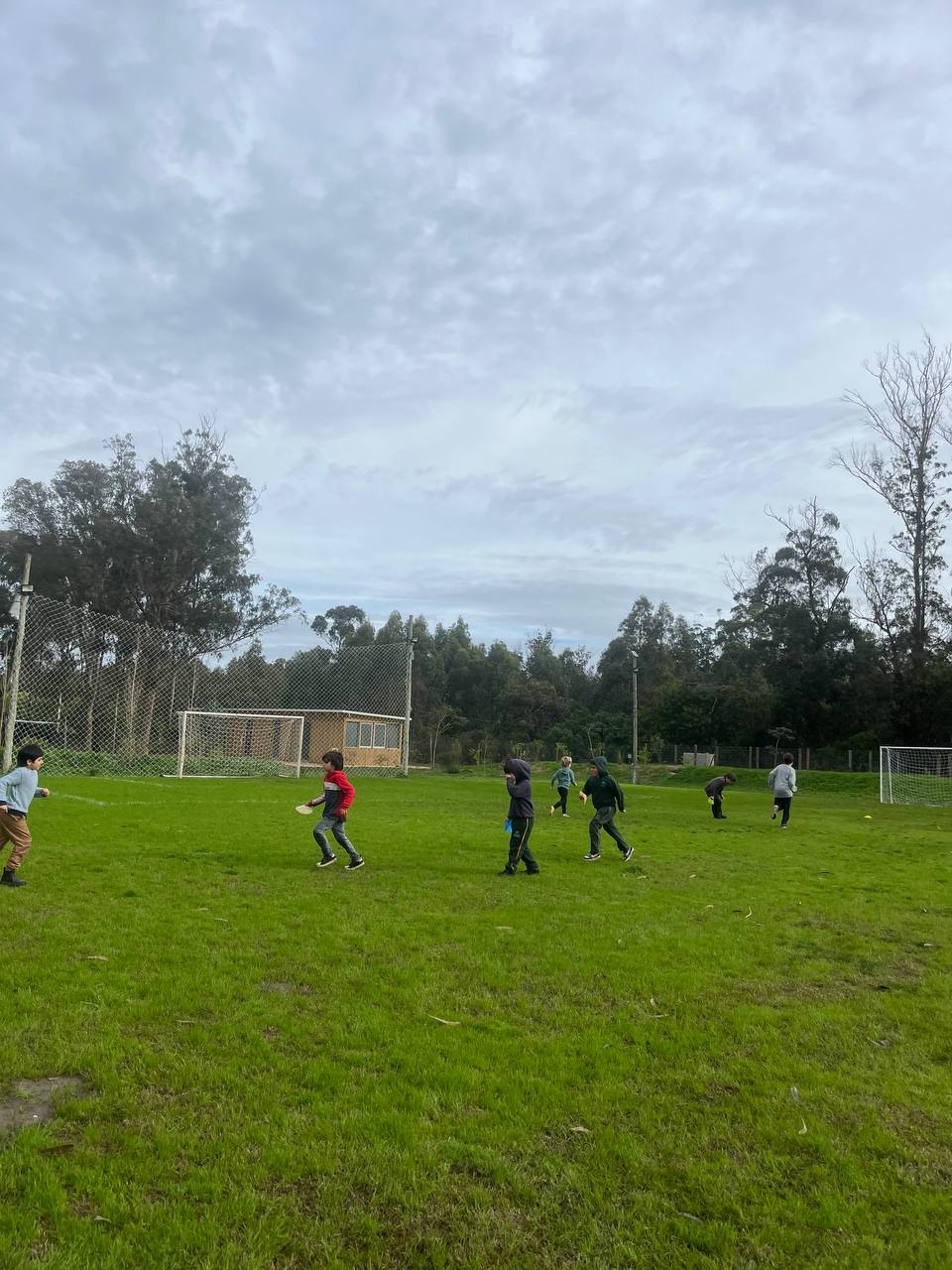 Niños y niñas corriendo en la canchita durante el juego de llevar materiales a sus bases