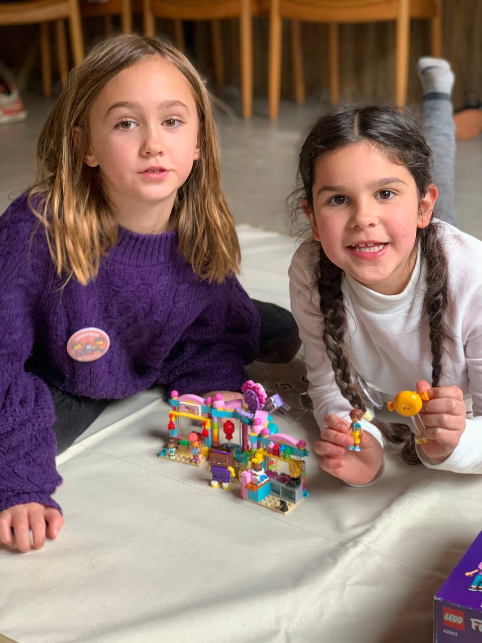 Niños y niñas muestran los sets de LEGO que están construyendo, junto con sus instrucciones.