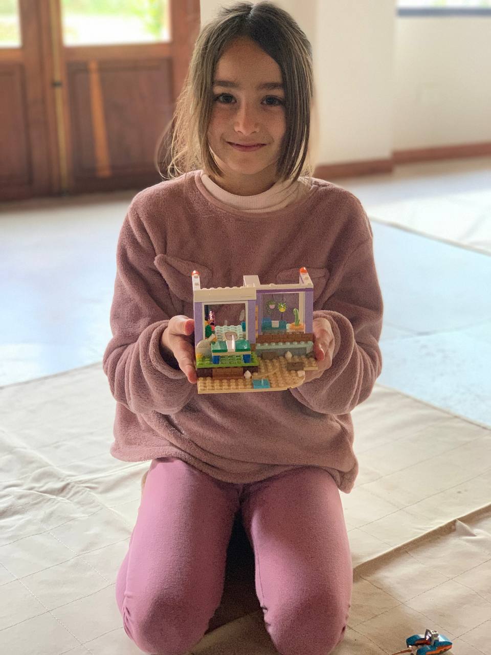 Niños y niñas muestran los sets de LEGO que están construyendo, junto con sus instrucciones.