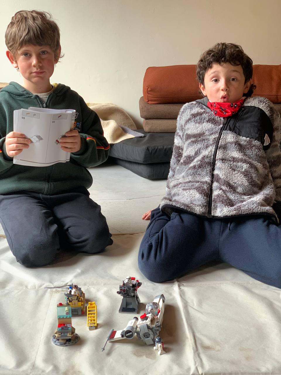 Niños y niñas muestran los sets de LEGO que están construyendo, junto con sus instrucciones.