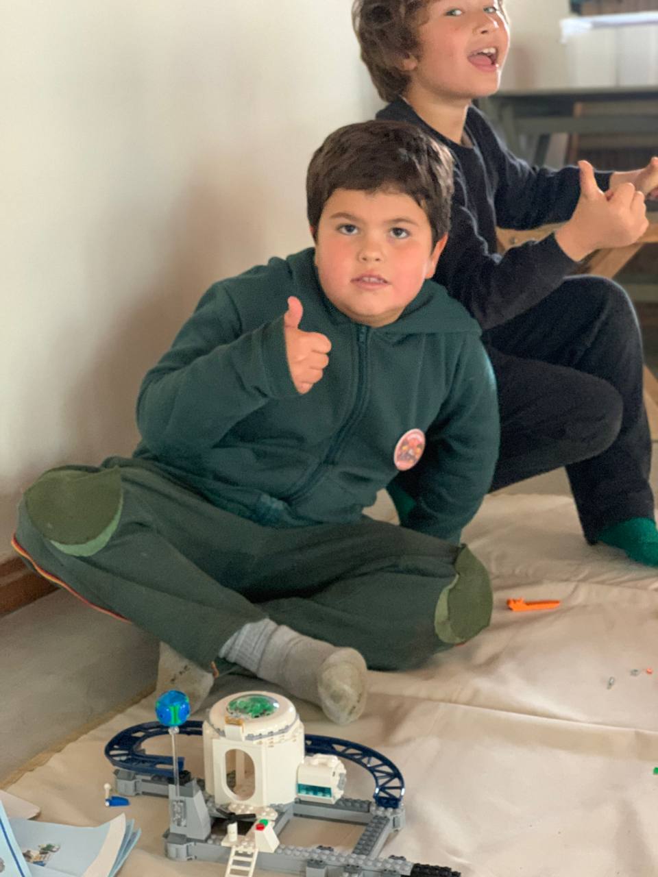 Niños y niñas muestran los sets de LEGO que están construyendo, junto con sus instrucciones.