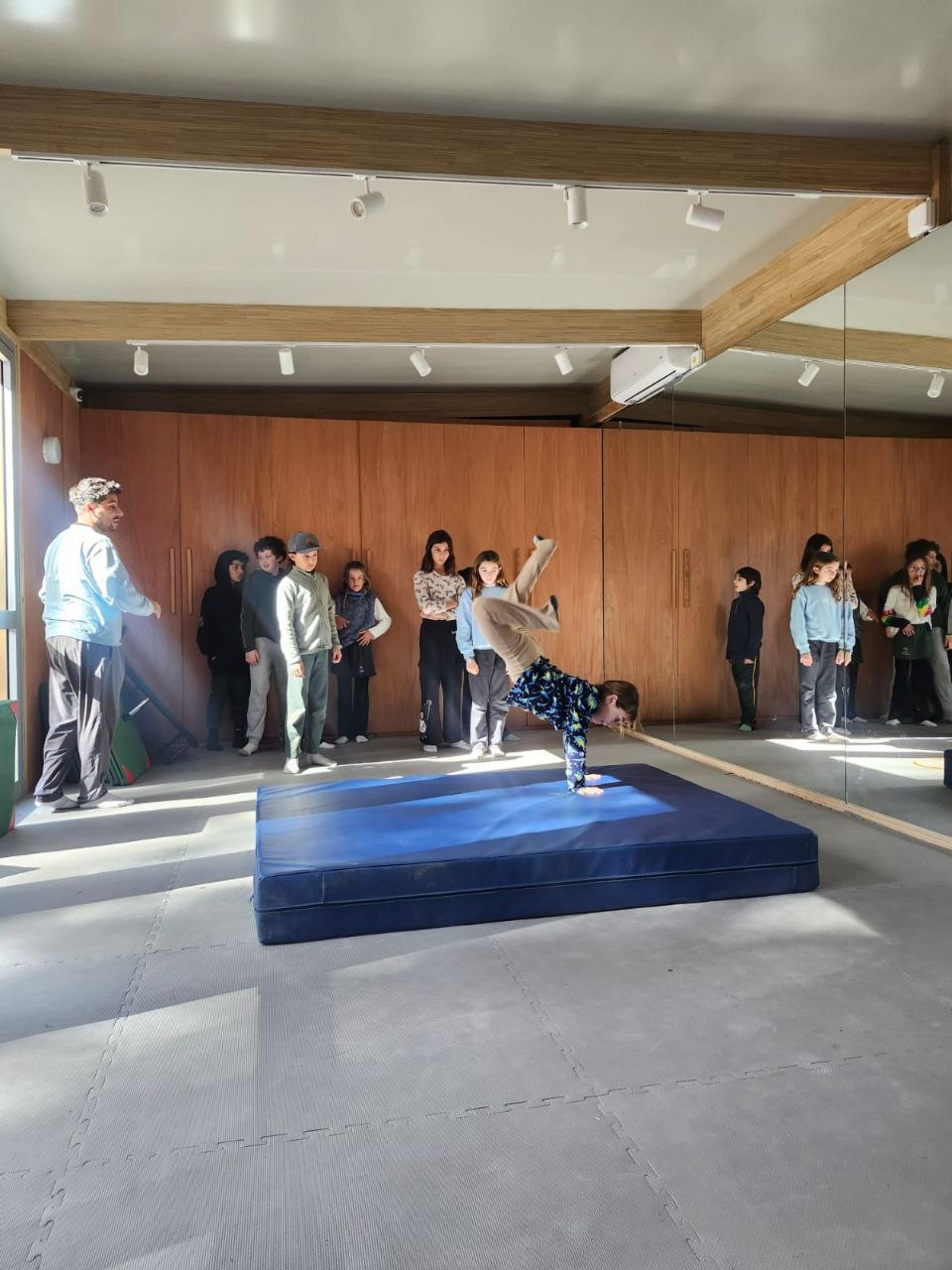 Registro visual de la sesión de gimnasia en sala: prácticas de roles, movimientos invertidos y desplazamientos sobre colchonetas.