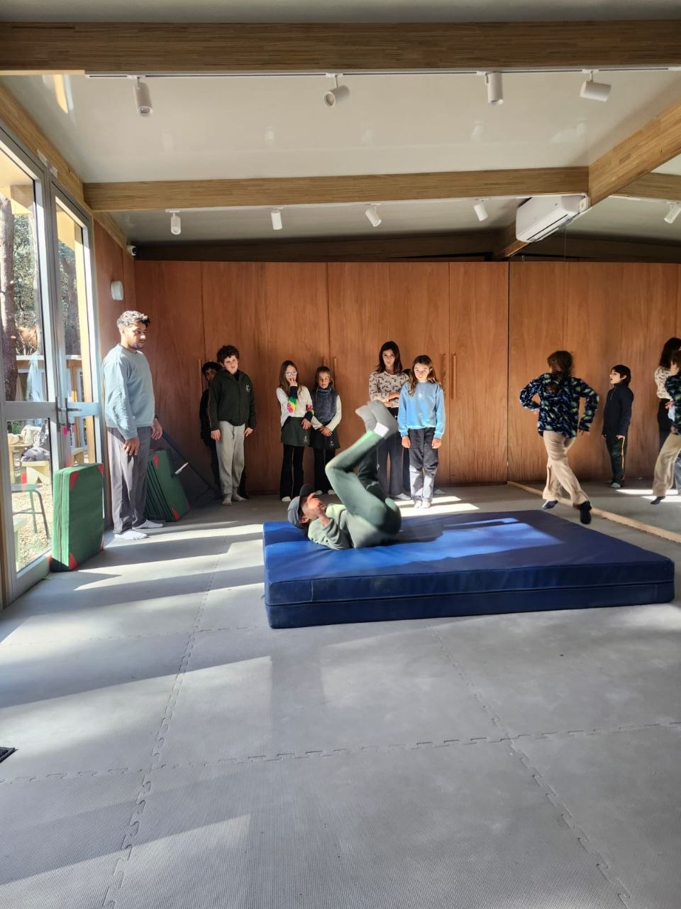 Registro visual de la sesión de gimnasia en sala: prácticas de roles, movimientos invertidos y desplazamientos sobre colchonetas.