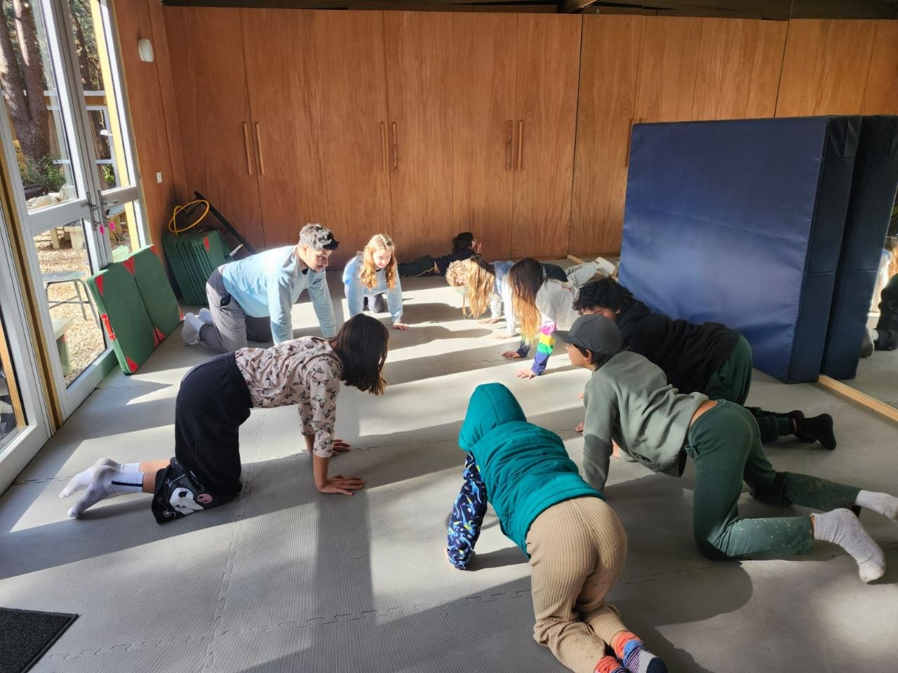 Registro visual de la sesión de gimnasia en sala: prácticas de roles, movimientos invertidos y desplazamientos sobre colchonetas.
